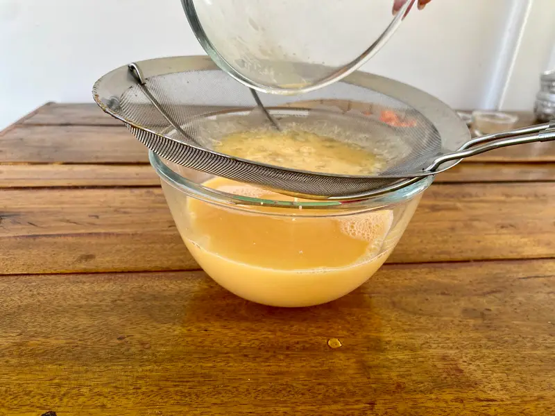 Straining the steamed egg mixture through a fine-mesh sieve.