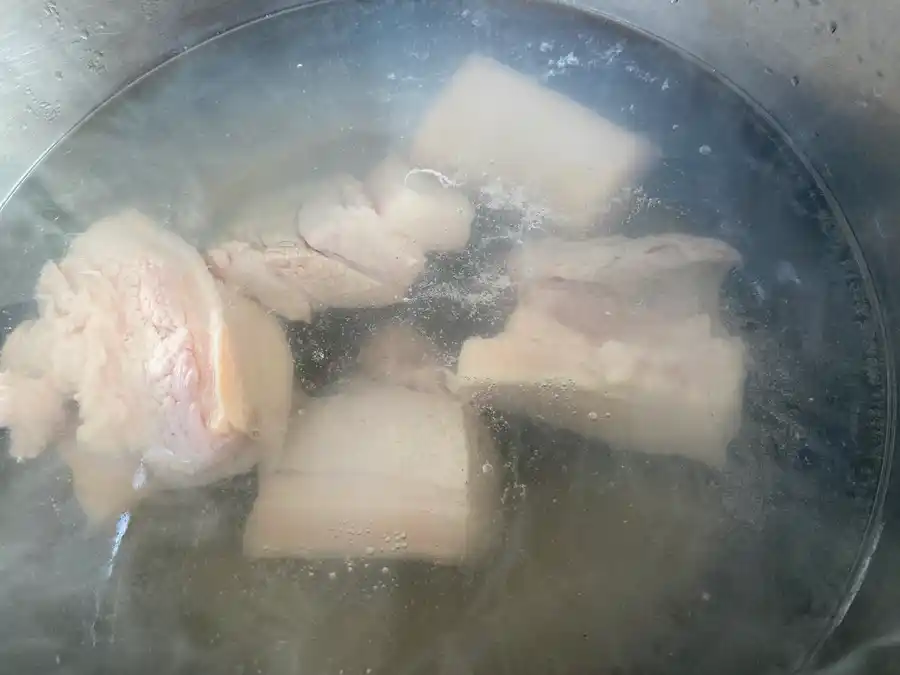 5 pieces of pork belly in a cooking pot filled with water.