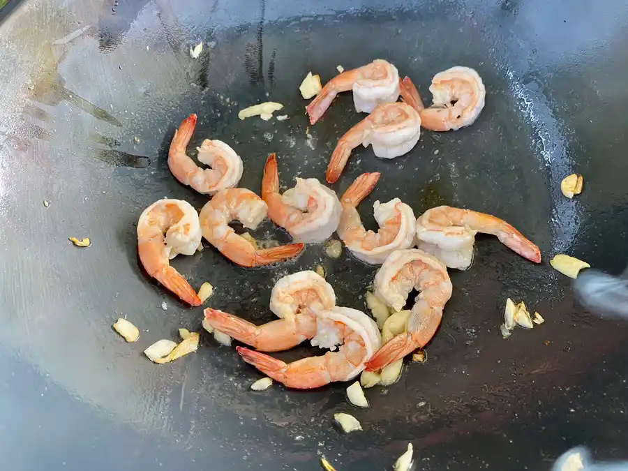 Close-up of cooked shrimp and garlic in a wok.