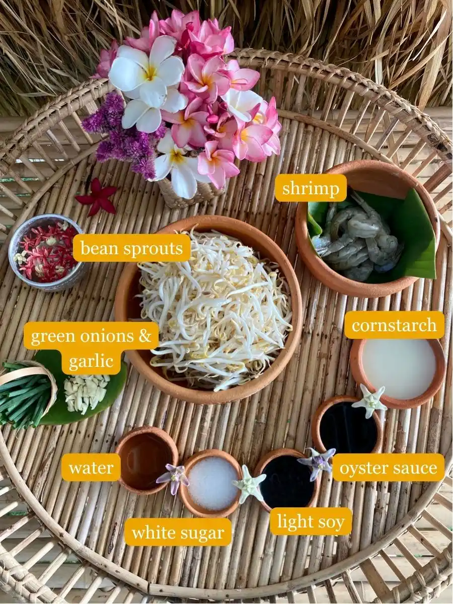 Shrimp, cornstarch, oyster sauce, light soy sauce, water, green onions, garlic, and bean sprouts with flowers on top of a bamboo serving tray.