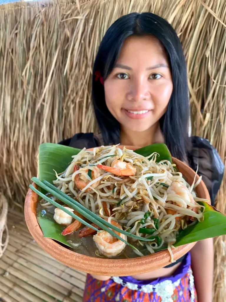 Me holding a clay dish with shrimp with bean sprouts stir-fry.