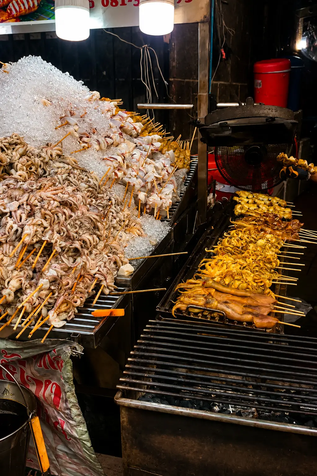 Thai grilled squid cooking over a charcoal grill at a Bangkok street food market.