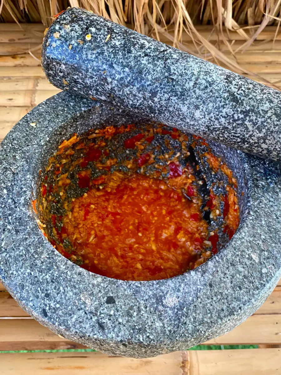 Freshly ground spicy vinegar based dipping sauce with chilies in a granite mortar with pestle.