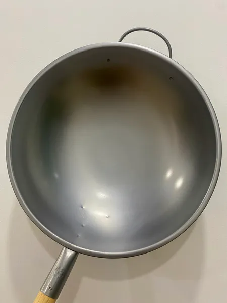 A steel wok pan on a white background.