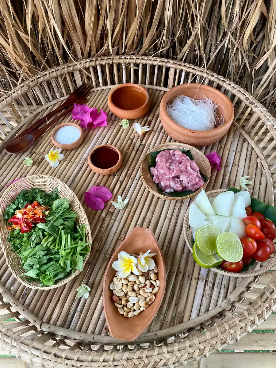 Ingredients for yum woon sen: glass noodles, ground pork, fish sauce, white sugar, lime, pickled garlic water, chilies, vegetables, and roasted peanuts.