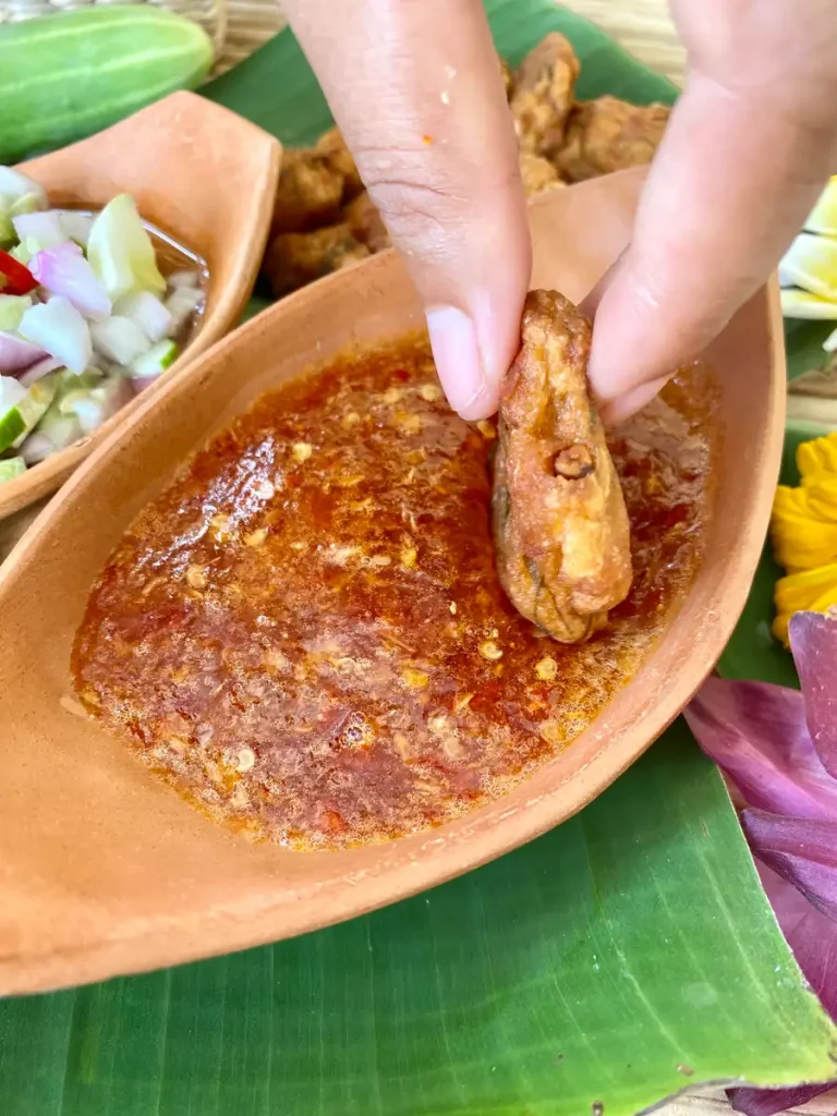 Spicy Thai chili condiment, with fish cake dipping into the sauce.