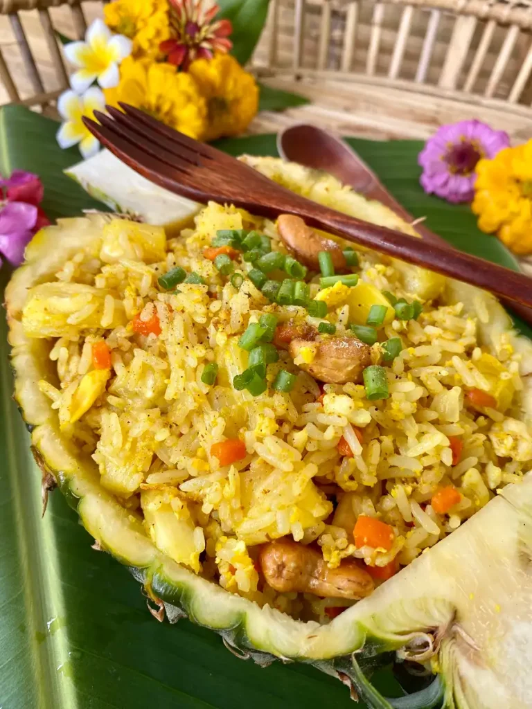 Chicken pineapple fried rice with a wooden fork and flowers.