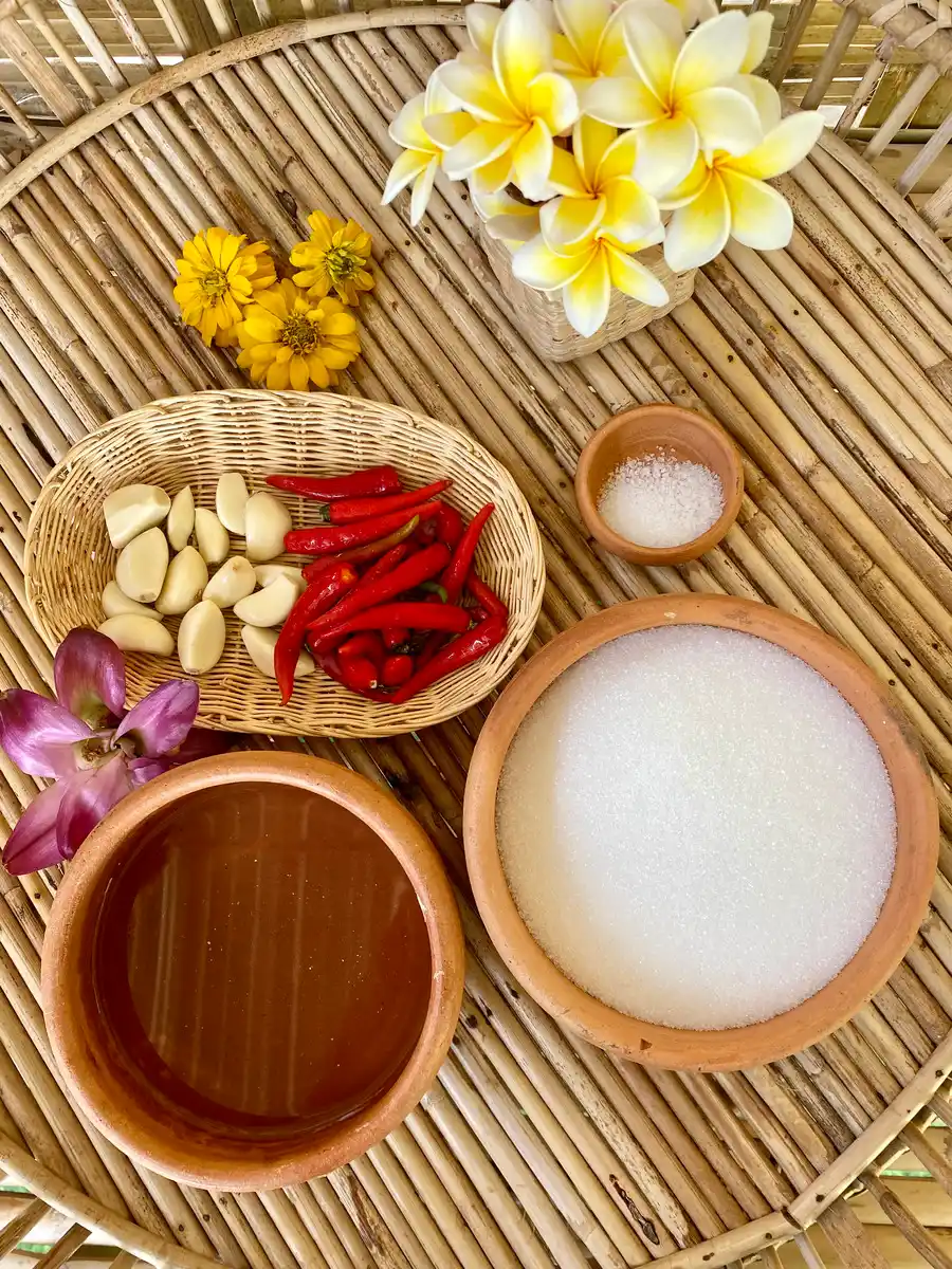 Ingredients for Thai sweet chili sauce: red chilies, garlic, white vinegar, white sugar, salt, and garlic on a bamboo serving tray.