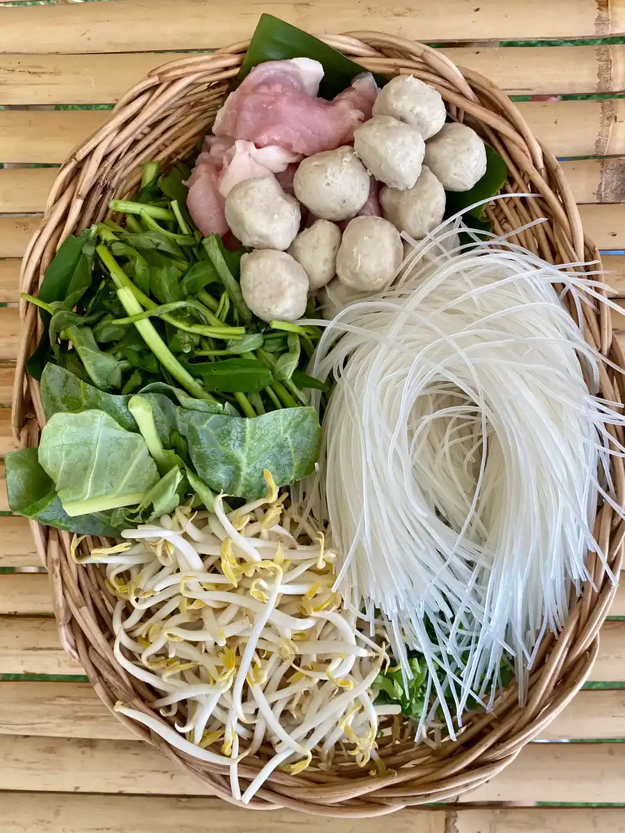Ingredients for dry tom yum noodles: vegetables, meat, and dry rice noodles.