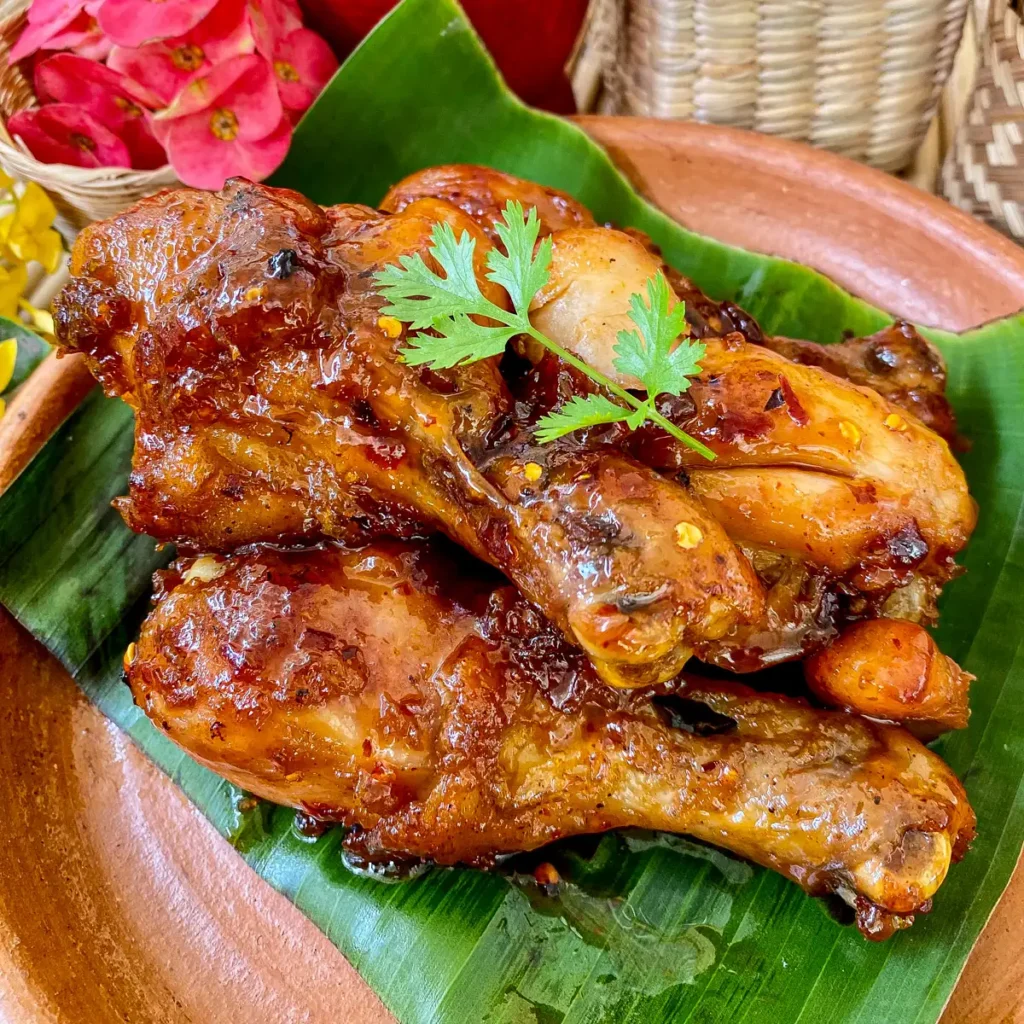 Spicy fried chicken without buttermilk glazed in chili paste on a banana leaf-lined plate.