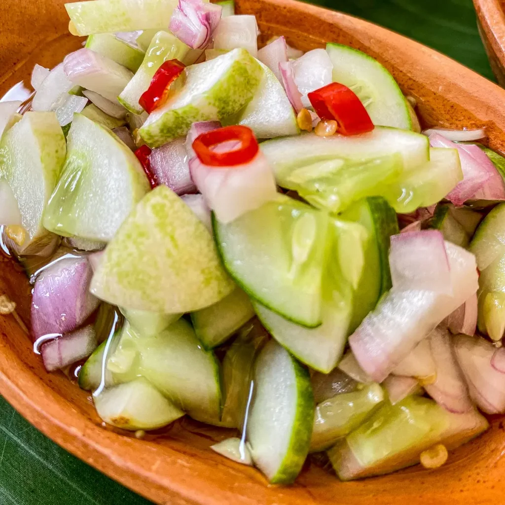 Thai cucumber salad for satay, ajaad featuring sliced cucumber, red chili, and purple shallots in a sweet and sour dressing.