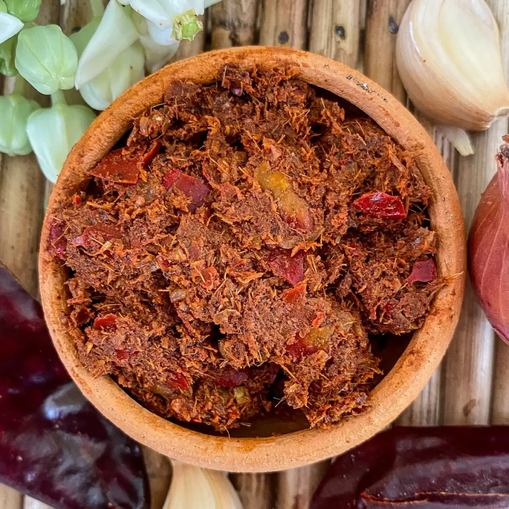 Homemade Thai massaman curry paste in a clay bowl, packed with dried red chilies, garlic, and aromatic spices.