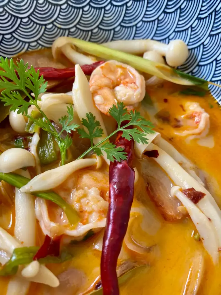 Close-up of tom yum shrimp in a patterned bowl.