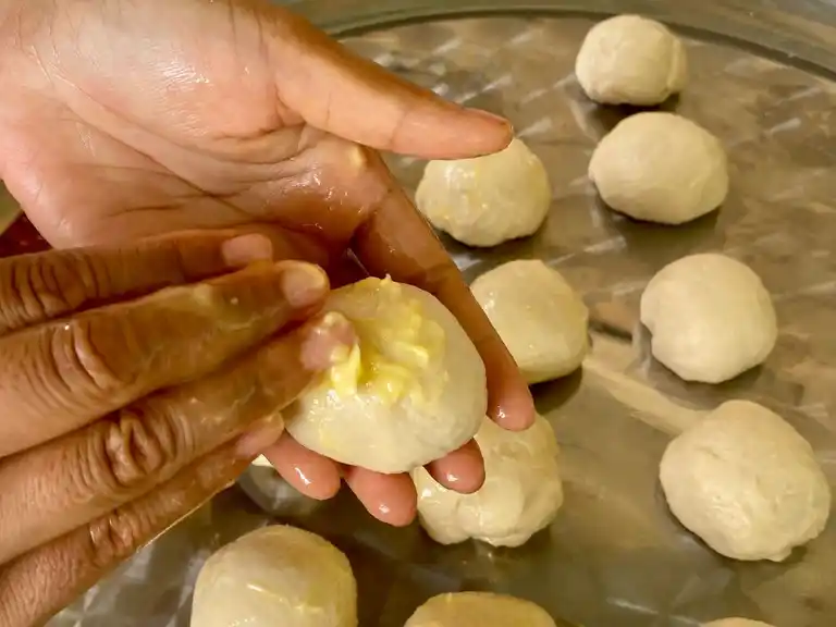 Spreading butter on Thai roti dough balls before second rest.