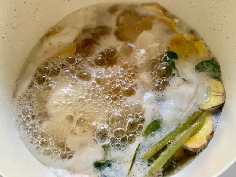 Lemongrass, galangal, and kaffir lime leaves gently simmering in the broth base.