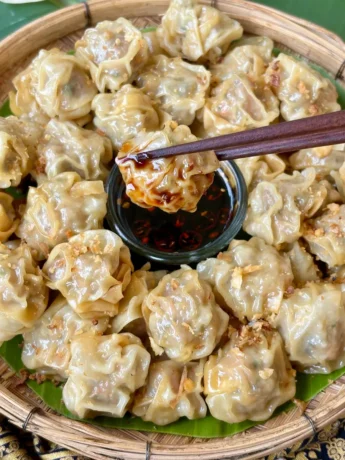 Steamed kanom jeeb, Thai dumplings, with crispy garlic topping, served with a spicy soy dipping sauce.