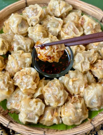 Steamed kanom jeeb, Thai dumplings, with crispy garlic topping, served with a spicy soy dipping sauce.