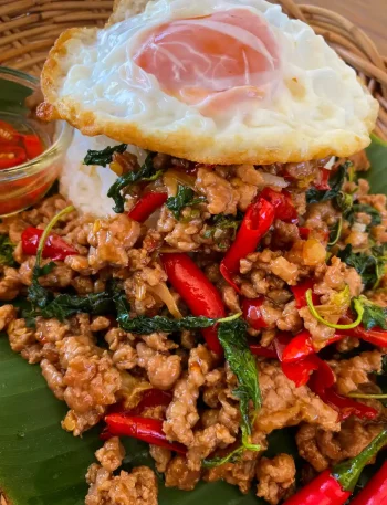Authentic pad kra pao pork served over rice with a fried egg.