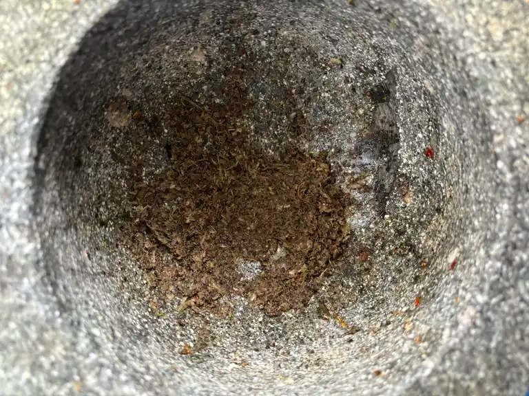 Freshly pounded coriander root, peppercorns, and garlic in a mortar.