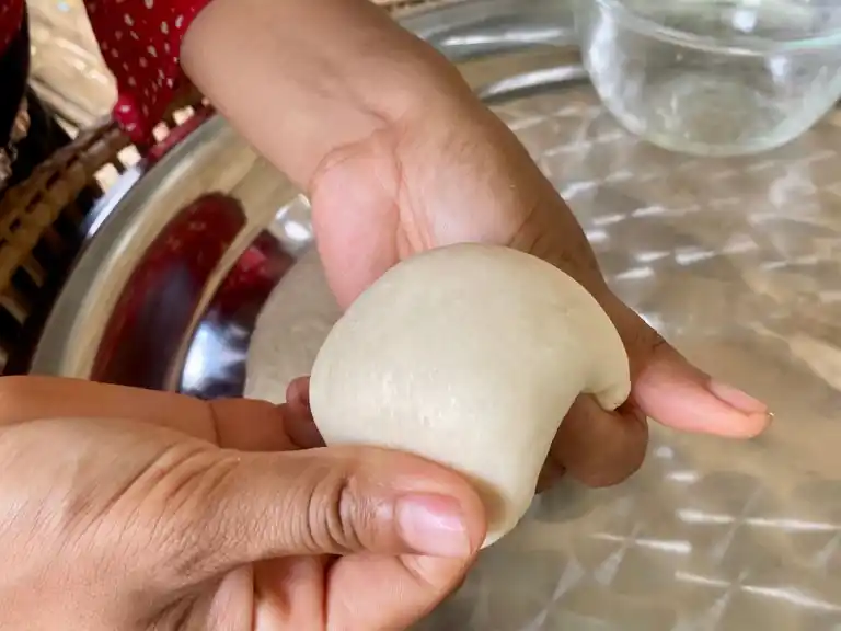 Shaping a smooth Thai roti dough ball by hand.