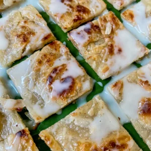 Thai roti dessert topped with condensed milk, showing crispy edges and soft layers.