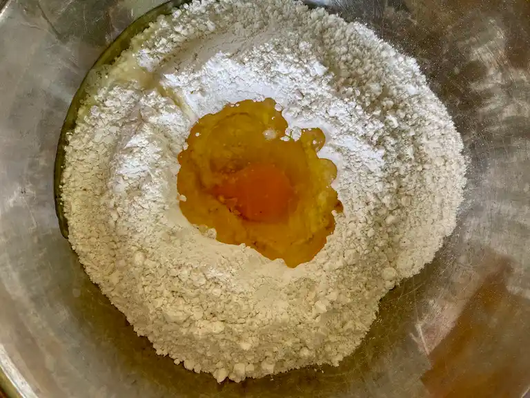 Flour with egg in a mixing bowl to prepare traditional Thai roti dough.