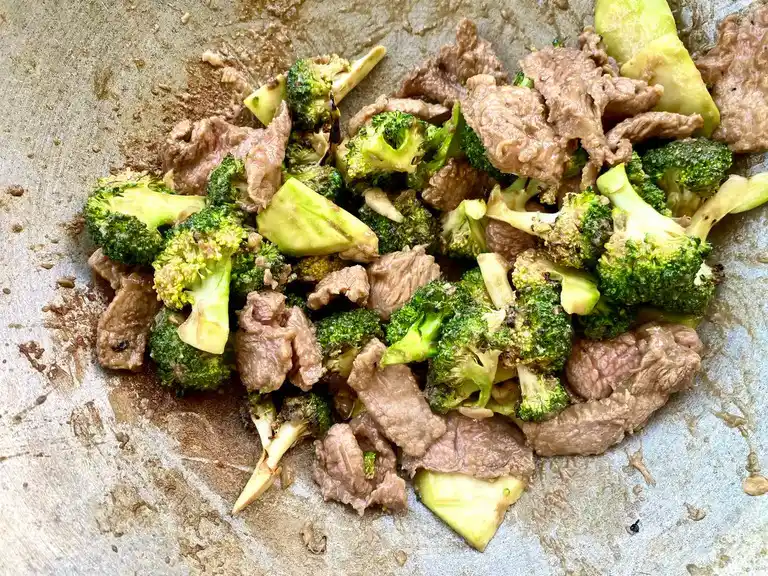 Final stir-fried beef and broccoli mixed in a wok, ready to serve.