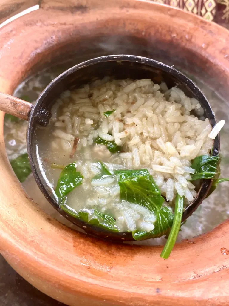 Khao tom, Thai rice soup, in a wooden ladle over a clay pot.