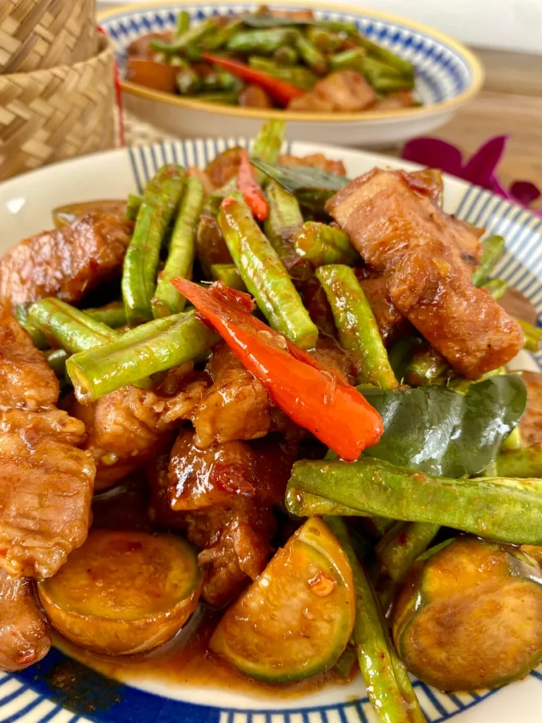 Pad prik king, Thai red curry stir-fry, with pork and green beans served in a white dish.