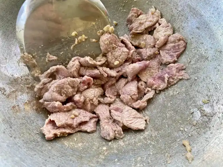 Thinly sliced beef seared with golden garlic in a wok.