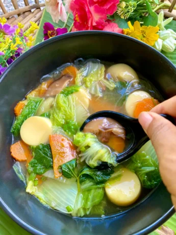 Thai vegetable soup, tom jued, in a black bowl.