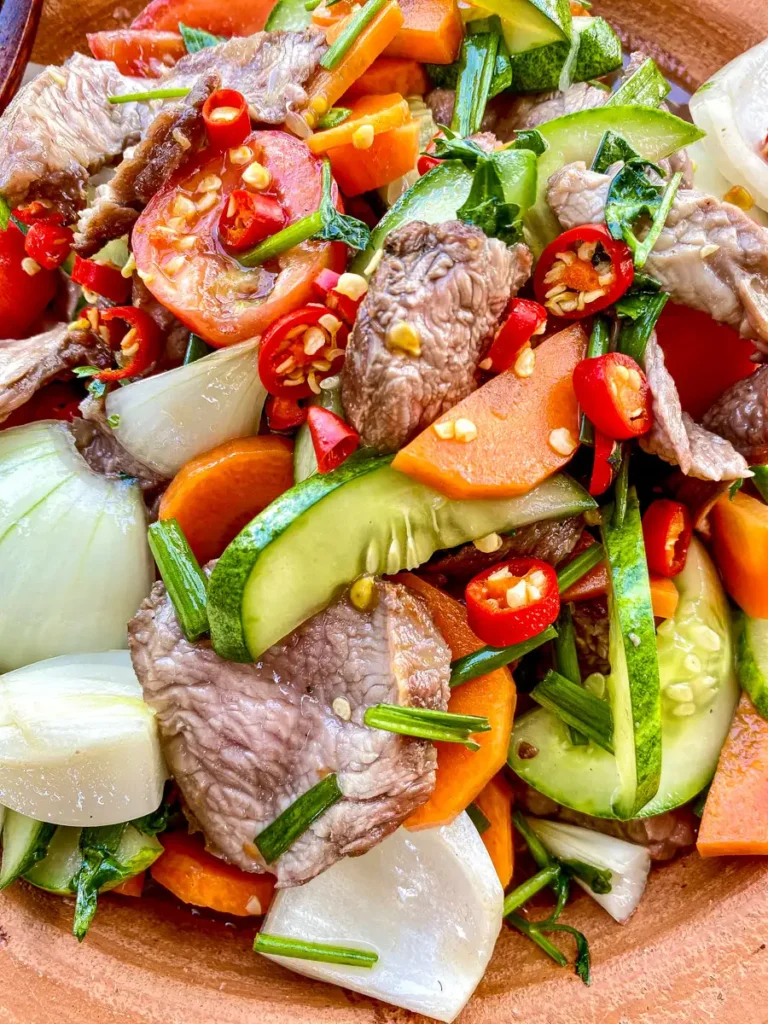 Yum nua, Thai spicy beef salad with tender beef, fresh vegetables, and red chili flakes for a bold, vibrant look.