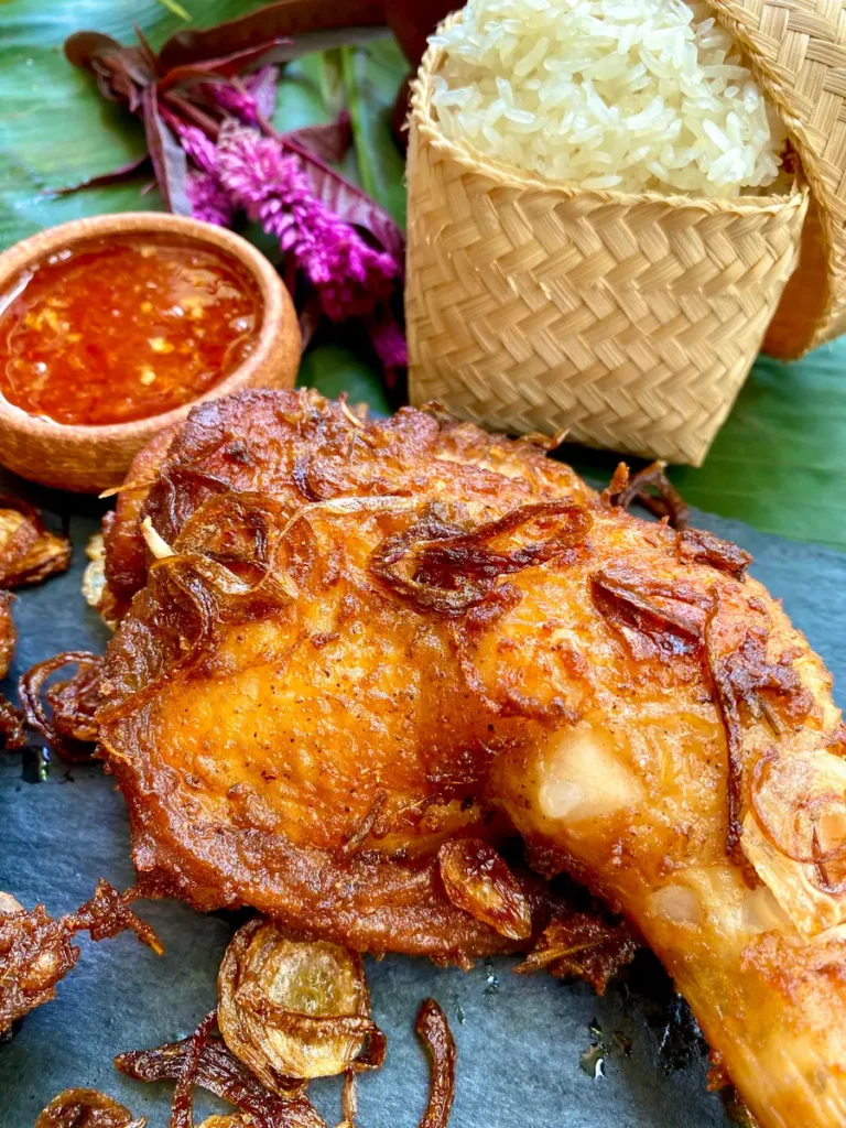Hat yai fried chicken with sweet chili sauce and Thai sticky rice in bamboo basket.