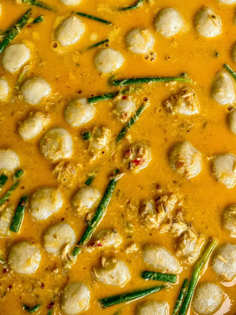 Close-up of nam ya fish curry with fish balls and green onions.