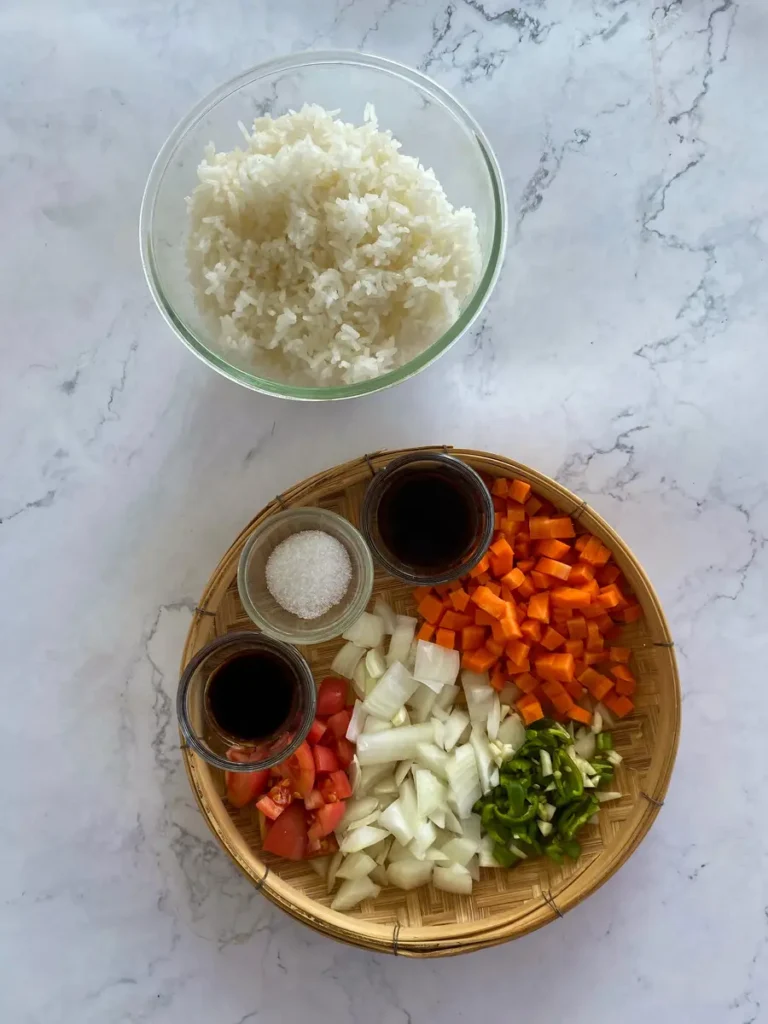 Ingredients to make this Thai fried rice recipe: rice, mushroom soy sauce, light soy sauce, white sugar, carrots, tomatoes, green onions, green bell peppers, onions, and garlic.