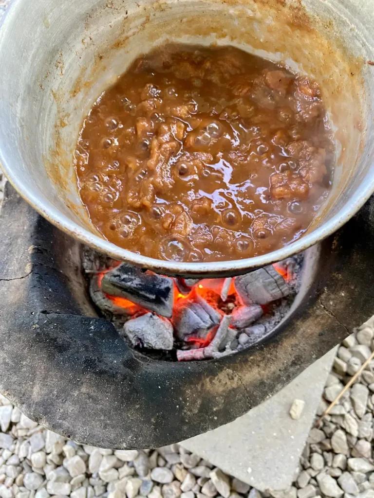 Bubbling tamarind pulp simmering in a traditional pot over an open charcoal fire.