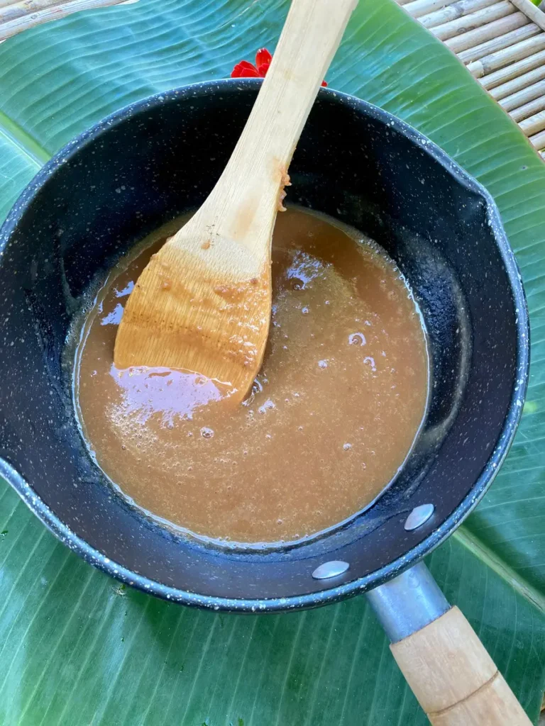 Top-down view of a pot with tamarind concentrate and a wooden spoon in it.