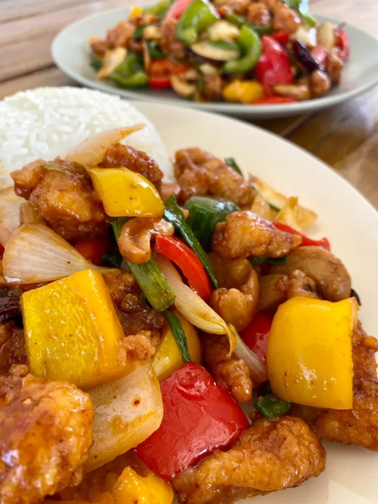 Two white dishes with Thai cashew chicken stir-fry and white rice.