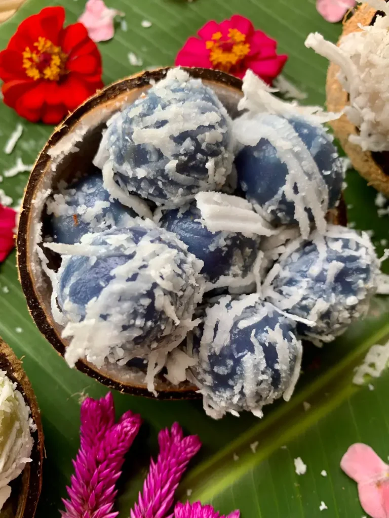 Close-up of blue khanom tom, topped with shredded coconut.