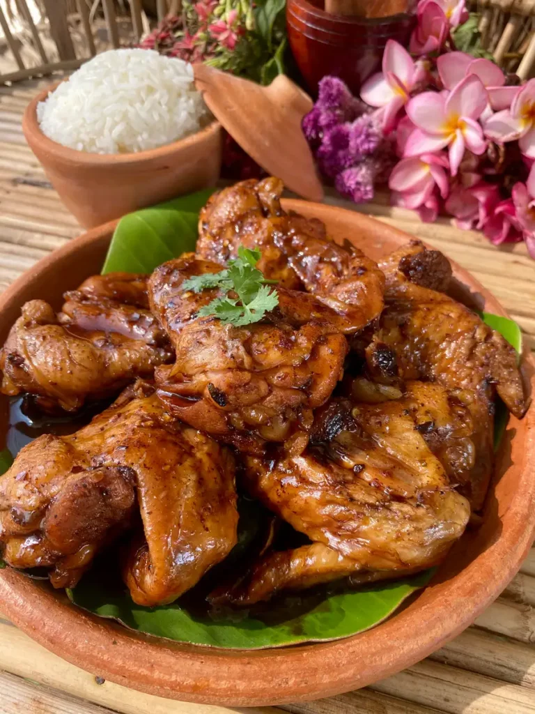 Coke chicken wings in a clay dish with white rice.