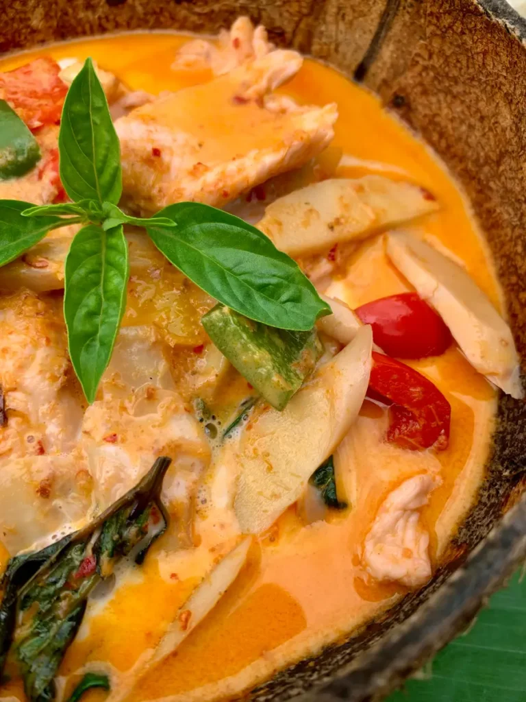 Close-up of gaeng daeng ; Thai red curry with chicken and vegetables in a coconut shell.