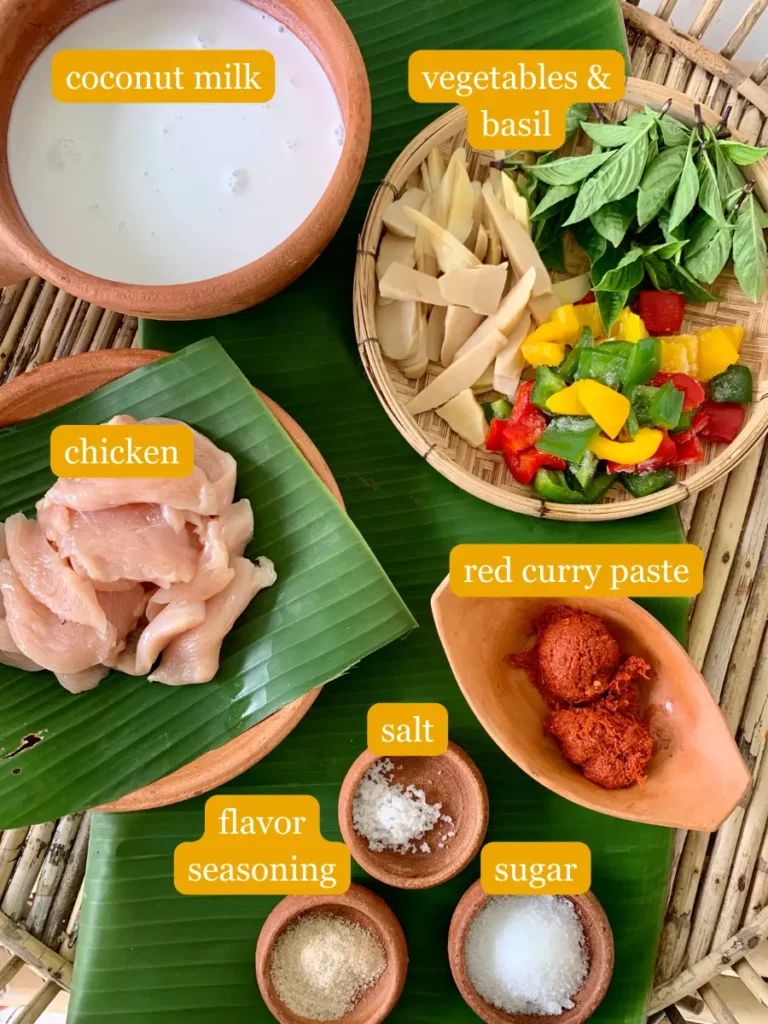 Bird's eye view of gaeng daeng ingredients; coconut milk, bell peppers, bamboo shoots, Thai basil, chicken, red curry paste, salt, flavor seasoning, and white sugar.