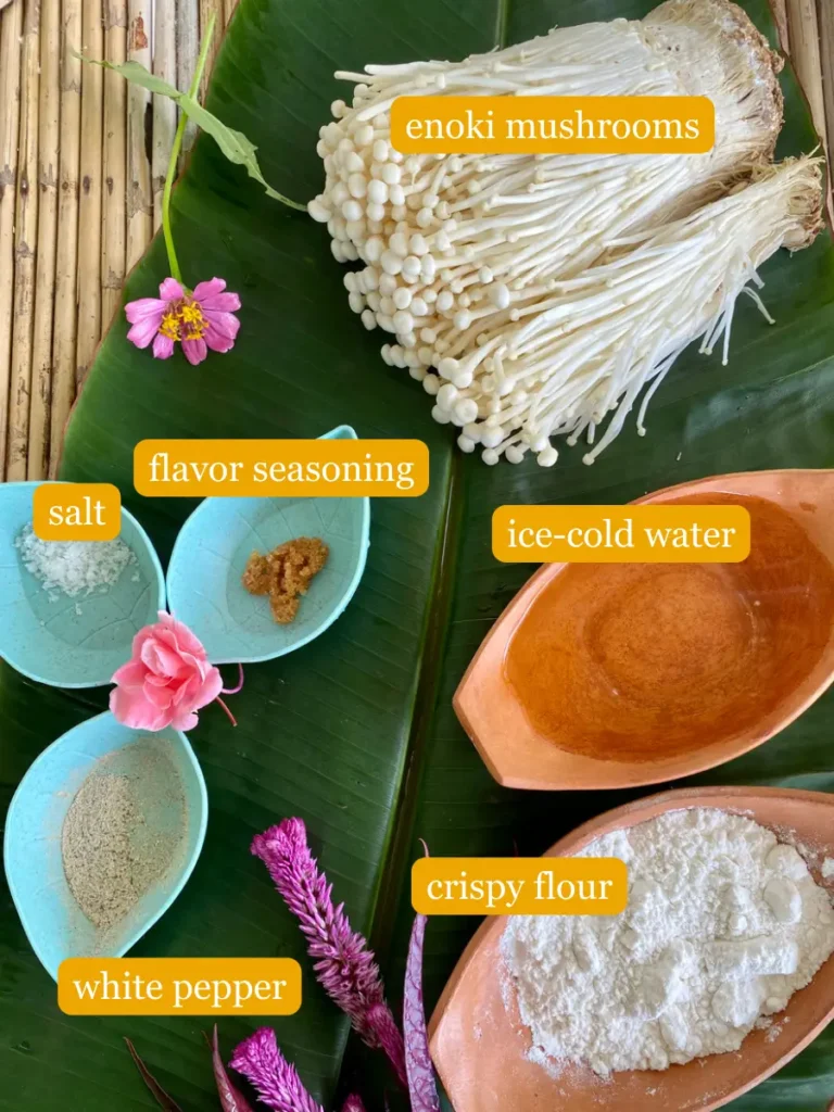 Bird's eye view of the recipe ingredients; enoki mushrooms, salt, flavor seasoning, ice-cold water, crispy flour, and white pepper.