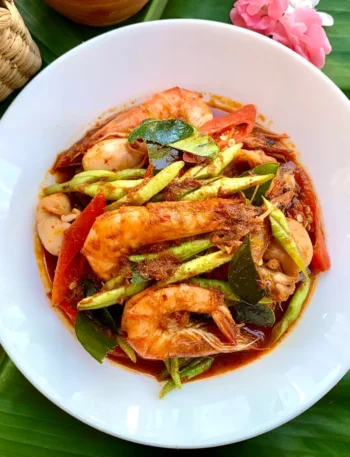 Pad ped talay, spicy Thai seafood stir-fry with beans, shrimp, and squid, served in a white dish.