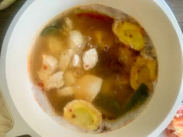 Tom yum broth turning red from chili paste and seasoning.