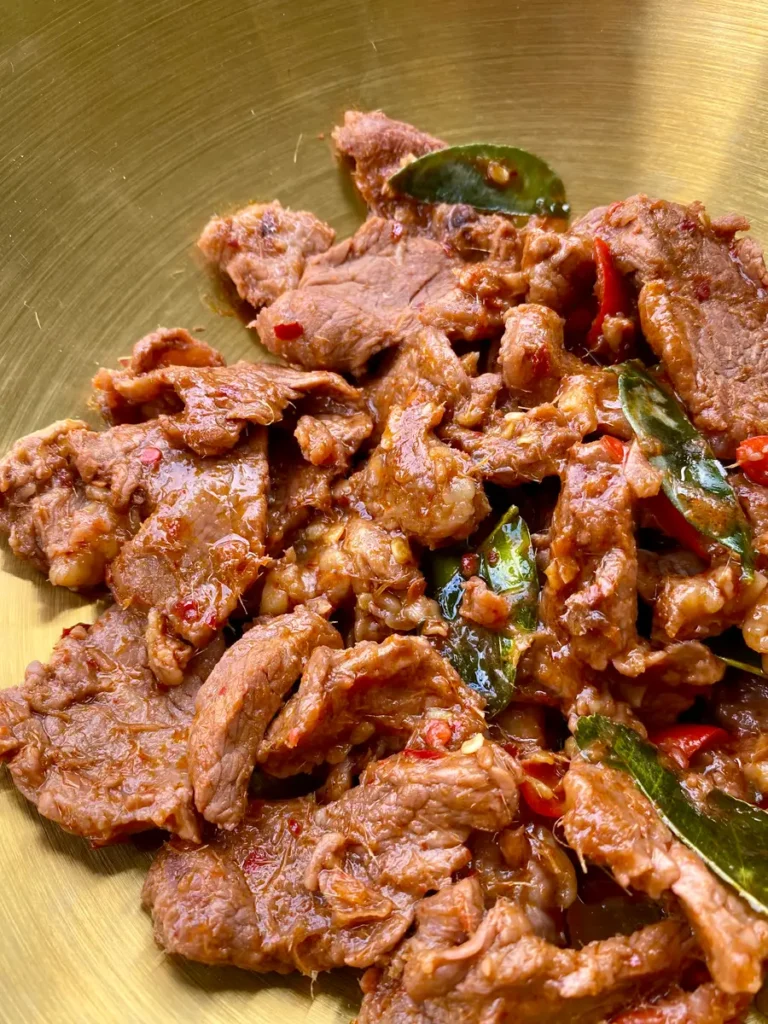 Close-up of spicy beef stir-fry in a golden dish.