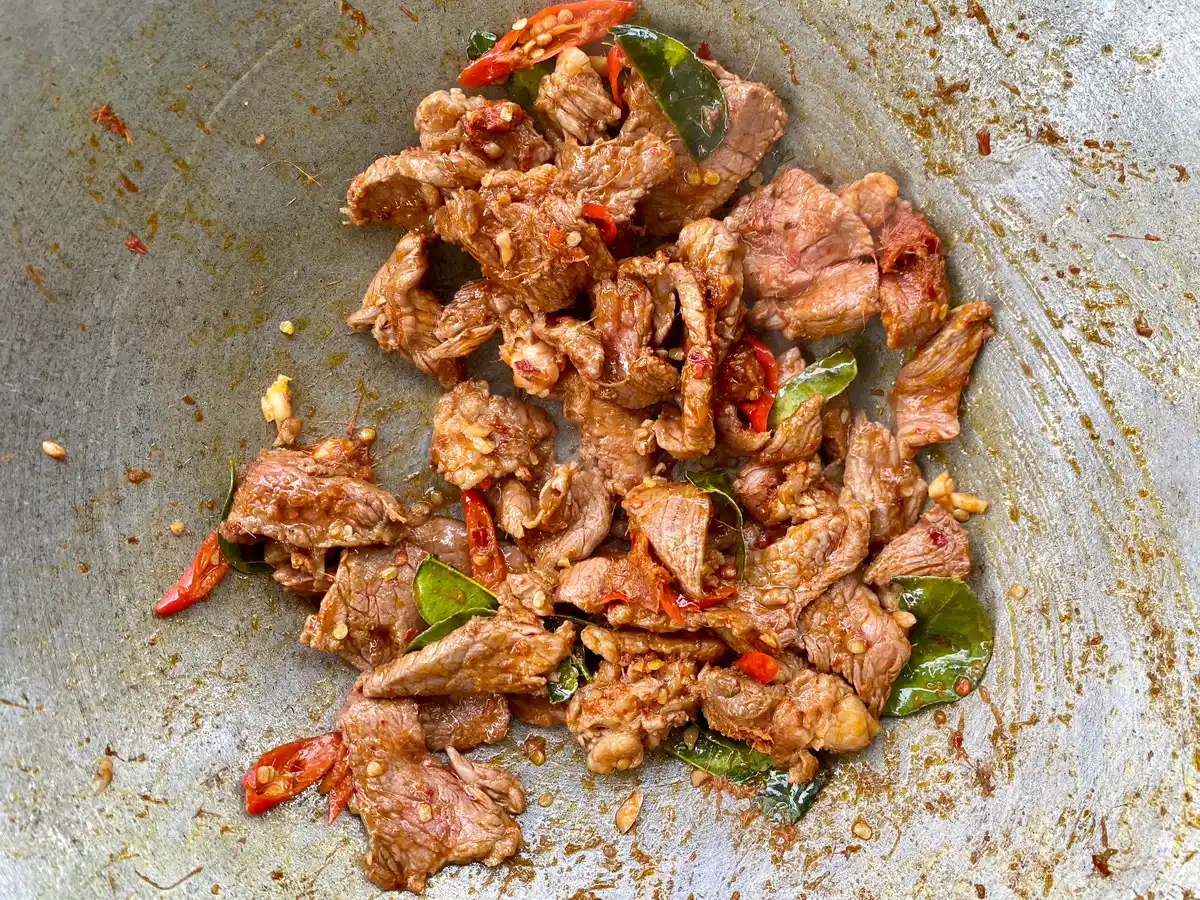 Close-up of stir-fried beef with chilies, garlic, and makrut lime leaves.