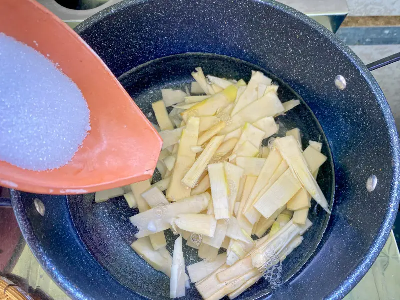 Blanching fresh bamboo shoots with sugar in a pot.