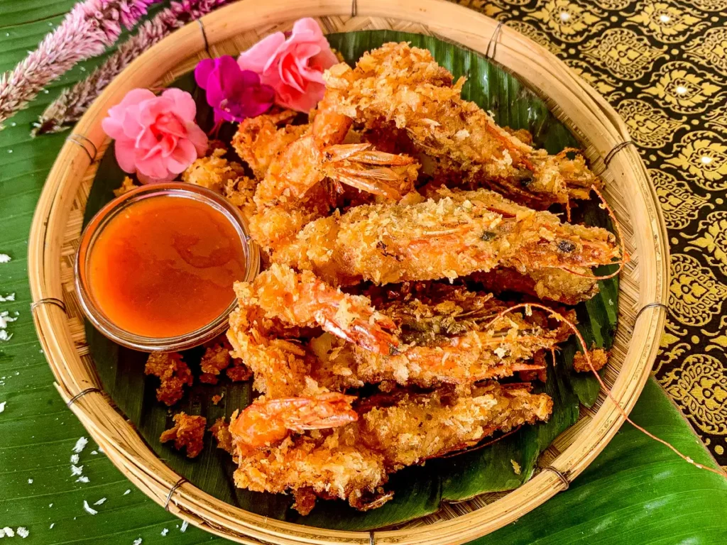 Goong tod fried prawns served with Thai sweet chili dipping sauce on a banana leaf platter.