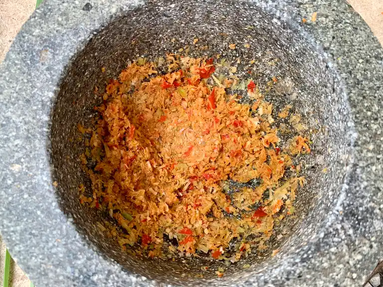 Crushed lemongrass, garlic, and chili paste in a granite mortar.